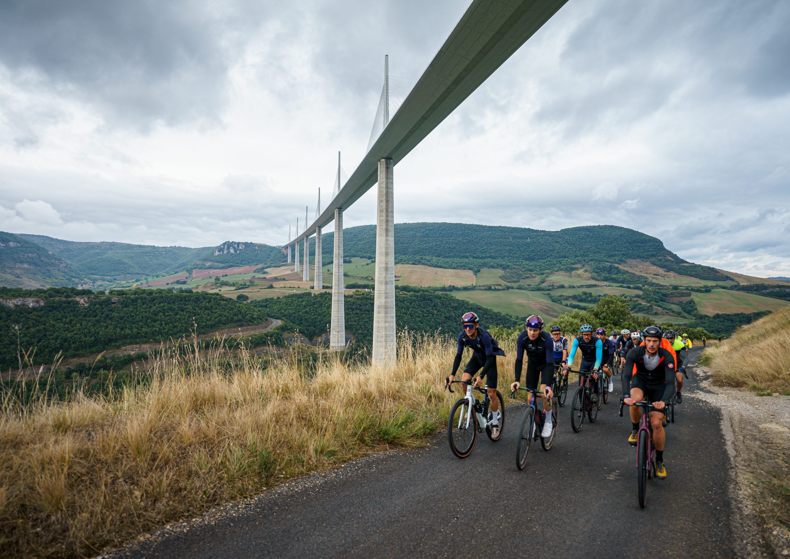 cyclistes qui passent sous le viaduc de millau